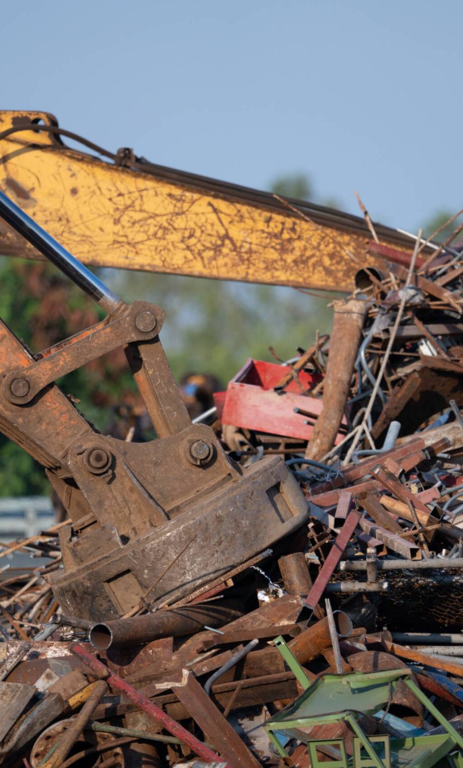 Excavator magnet lifting steel scraps from recycling materials pile at scrap yard in recycling factory. Excavator with electro and magnetic sucker magnet chuck. Special excavator. Scrap metal magnet.